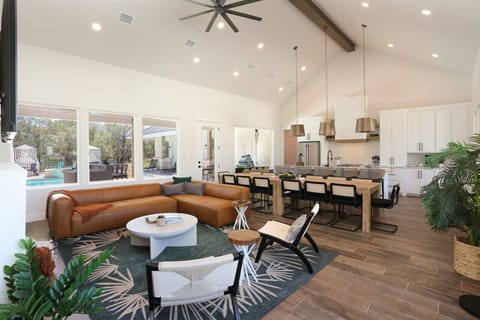 Spacious open-concept living room with a cozy sectional, large kitchen, and pool view, perfect for family gatherings and relaxation.