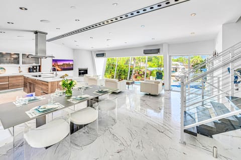 The open-concept living, dining, and chef's kitchen are bathed overlooking the tranquil canal and heated pool.