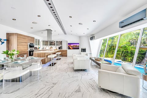 The open-concept living, dining, and chef's kitchen are bathed overlooking the tranquil canal and heated pool.