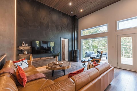 Living area with sectional sofa, TV, and views of the forested outdoors