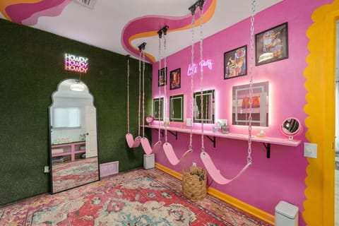 Vibrant room with swings, neon lights, and whimsical decor—perfect for fun selfies!
