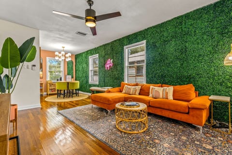 Feel the warmth and charm of our living room with its orange plush sofa, stylish grass wall design, and neon ‘hello gorgeous’ light for a touch of flair