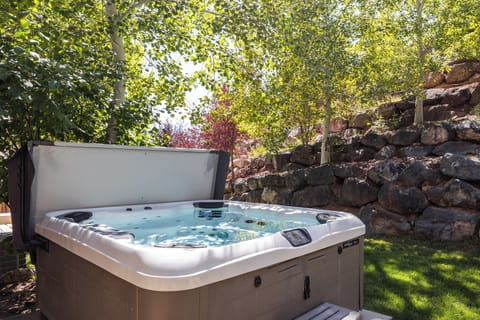 - Unwind in the outdoor hot tub surrounded by trees  
- Refresh after adventures in the warm bubbling spa  
- Relax beneath shaded greenery and natural rock setting