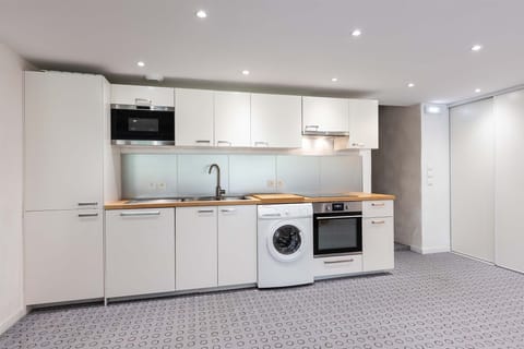 This sleek and modern kitchen is fully equipped with everything you need, including a washing machine, microwave, and oven. It offers a convenient space for preparing meals during your stay.