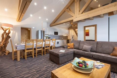 This open-plan living room features plush seating, high wooden ceilings, and rustic decor, creating a cozy and welcoming atmosphere for relaxing or socializing with family and friends.