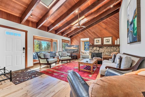 Living Room: Bright & open layout, couch, 4 chairs, gas fireplace, 65” Smart TV, skylights