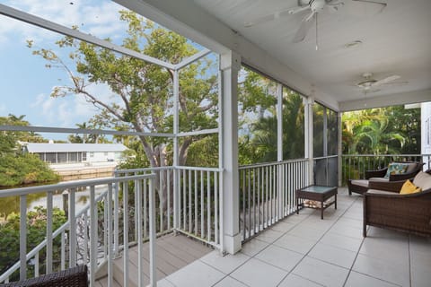 First floor patio with stairs to pool area and seating overlooking canal