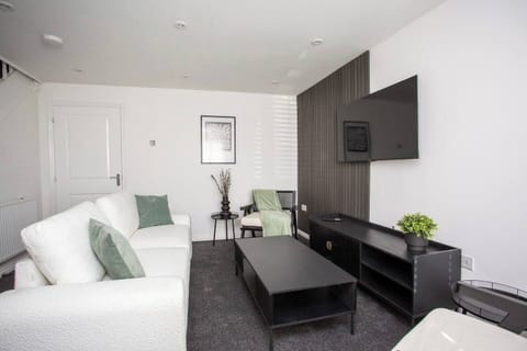 This living room features a bright and airy atmosphere, with its crisp white walls and matching white sofas that create a clean and elegant look as you sit right in front of the TV