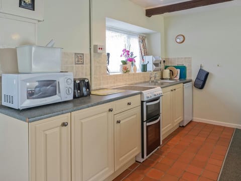 Kitchen area with electric cooker, under counter fridge and microwave