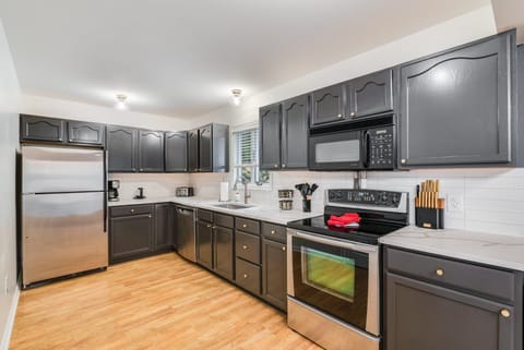Fully updated kitchen boasts dark cabinetry with quartz countertops and tiled backsplash and ample storage space. Perfect for family gatherings or group getaways.