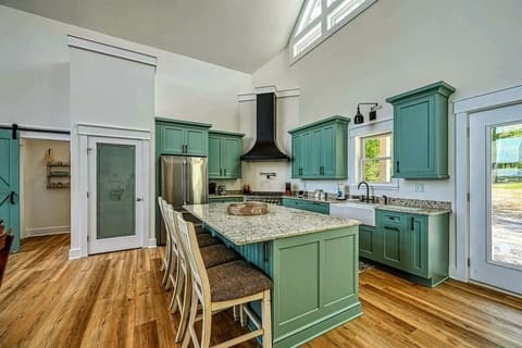 Spacious and modern kitchen with a large island, stylish green cabinetry, and plenty of natural light, perfect for cooking and entertaining