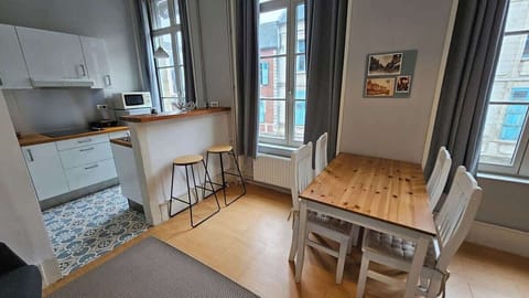 Salon ouvert sur la cuisine, avec canapé convertible pour une personne, télévision et table à manger pour quatre personnes.