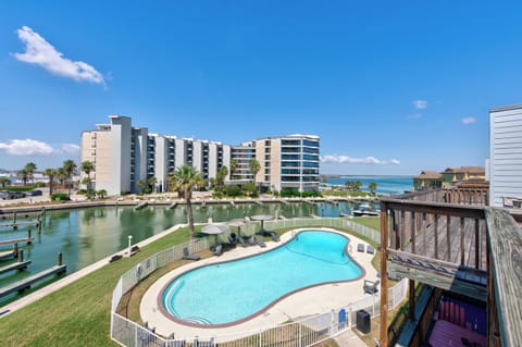 Waterfront resort complex featuring pool, marina, and modern accommodations under brilliant blue skies.