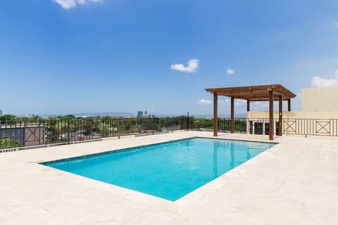 Sunlit pool terrace w/ pergola & sweeping city views, perfect for a refreshing dip under blue skies