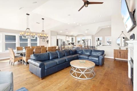 The bright and open Living Area offers cathedral ceilings, floor-to-ceiling windows, a wall-mounted flat-screen TV, and a gas fireplace for cozy evenings in the off-season.