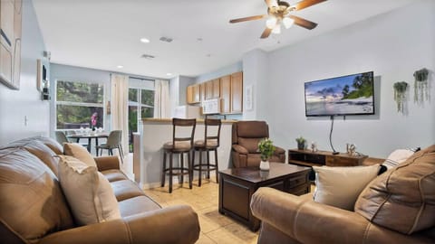 Cozy living room with leather seating and a wall-mounted television overlooking the dining area and kitchen.
