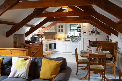 Living/kitchen/diner area: 3 seater sofa with bright coloured cushions, dining table with four chairs leading to fitted kitchen