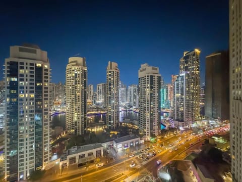 City skyline at night with illuminated skyscrapers, busy roads, and a river.