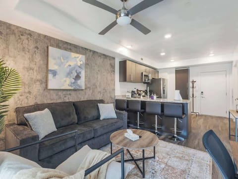 Relax in a stylish living area w/ plush sofa, textured accent wall & open flow into the kitchen