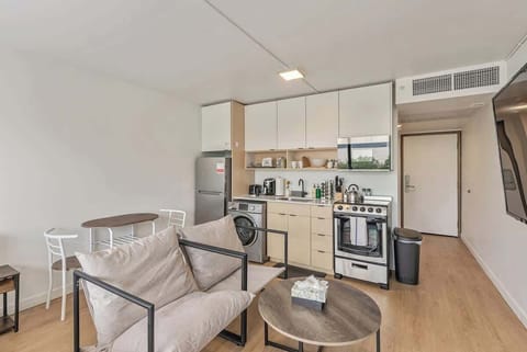Compact kitchen setup w/ stove, sink, washer & modern cabinetry for everyday convenience