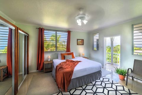 Experience luxury in this master bedroom with a king-sized bed dressed in bamboo sheets & a burnt orange throw. Large windows offer panoramic Atlantic Ocean views, complemented by stunning art & vibrant orange coconuts. Relax in your private suite