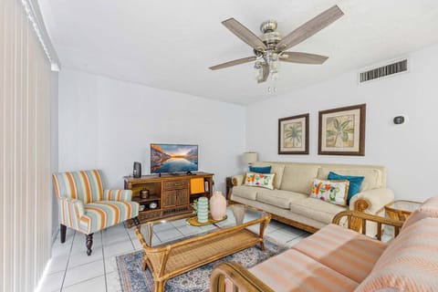 Relax in this cozy living room featuring a ceiling fan and comfortable seating with tropical-themed decor.
