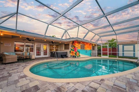 Screened in lanai with heated pool, hot tub, patio furniture, and string lights.