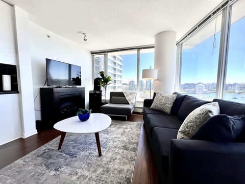 Bright and inviting, this modern living space offers the perfect spot to unwind. Guests can enjoy a cozy evening by the fireplace or take in stunning city and waterfront views through the floor-to-ceiling windows.
