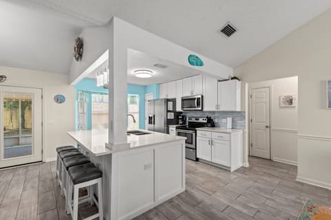 A bright central kitchen with a sleek breakfast bar, outdoor access, and a vibrant turquoise accent wall adding a pop of color.