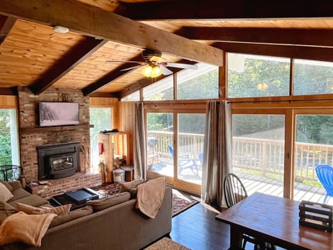 Bright and cozy living room with vaulted ceilings, wood-burning fireplace, Roku TV, and access to the large deck—perfect après-ski gathering space just minutes from Mount Snow.