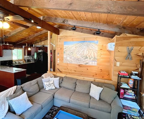 Spacious open-concept living room with large sectional, fully equipped kitchen, and ski trail décor—ideal Vermont ski house setup for families and groups.