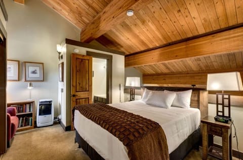 Luxuriate in this spacious bedroom featuring vaulted wooden ceilings and cozy decor.