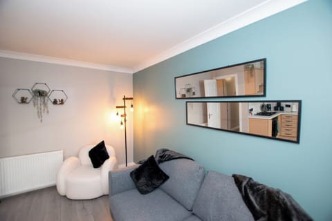 Modern living room with a 55" wall-hung TV, stylish double sofa bed, and boucle armchairs. Wood-pane (4)