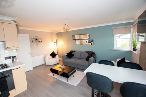 Modern living room with a 55" wall-hung TV, stylish double sofa bed, and boucle armchairs. Wood-pane (5)