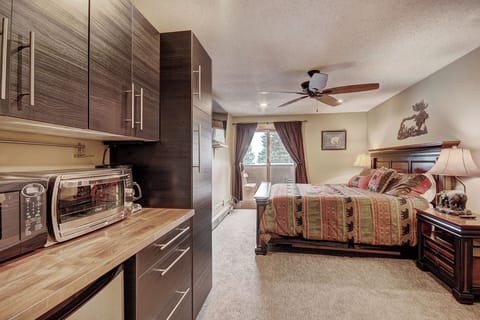 Hotel room featuring a king bed, private balcony, kitchenette area.