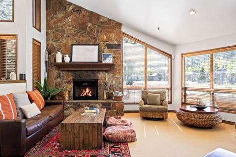 - Living room with stone fireplace and rustic cabin charm  
- Cozy seating with mountain views through large bright windows  
- Warm lodge style with modern comfort for group gatherings