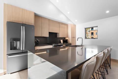 Full kitchen featuring stainless steel appliances, and breakfast bar with seating for five.