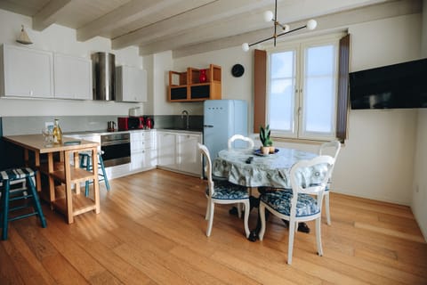 Fully equipped modern kitchen with bright dining area, wooden flooring, and designer details. Ideal for preparing and sharing meals in a welcoming setting in Peschiera del Garda.