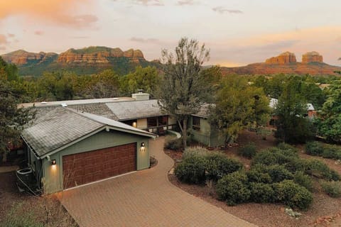 Modern property nestled among desert landscaping with dramatic red rock formations creating a stunning backdrop at sunset.