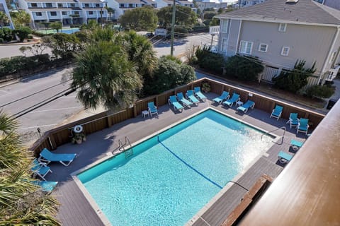Aerial view of property's swimming pool area with lounge chairs surrounded by tropical landscaping in a residential neighborhood.