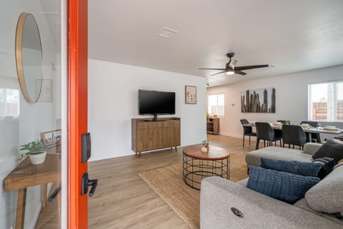 Living room features a L-shaped couch, smart TV with Roku, ceiling fan