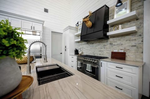 Elegant kitchen with marble countertops, farmhouse sink, and premium stainless steel appliances in upscale cabin