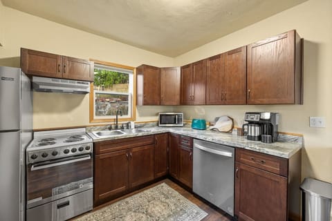 The kitchen counter is equipped with a coffee maker, microwave oven, dishwasher, refrigerator, and oven toaster, providing all the essentials for a functional and modern cooking space.