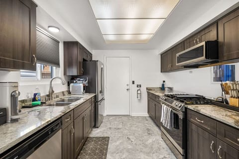 Sleek galley kitchen w/ stone counters, modern appliances, and streamlined layout for easy cooking.