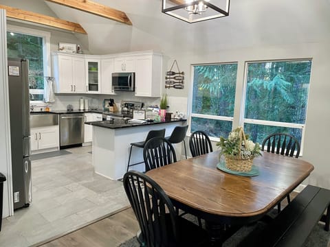 Open floor plan with the dining table looking out in the woods and firepit. 