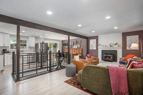 Colorful living room with open flow to dining, kitchen, and stylish staircase leading downstairs.