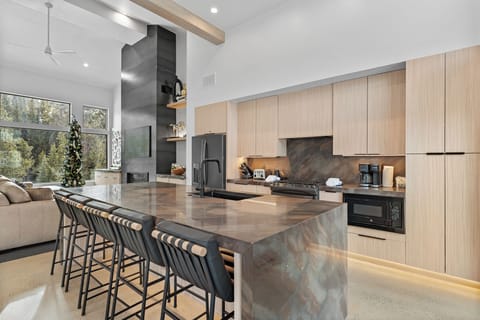 Full kitchen featuring stainless steel appliances, breakfast bar with seating for five, and balcony access.
