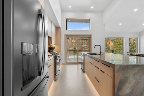 Full kitchen featuring stainless steel appliances, breakfast bar with seating for five, and balcony access.