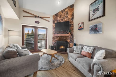Cozy up in the Timbernest living room, featuring a comfortable sofa, an inviting indoor fireplace, and a large TV for entertainment.