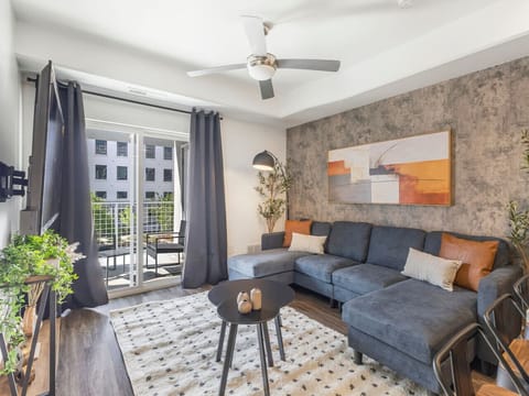 Stylish living room with a spacious sectional, modern décor, and balcony access for a bright and relaxing stay 🛋️🌿✨